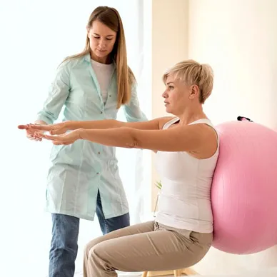 A physiotherapist guiding a patient through a seated exercise on a therapy ball.